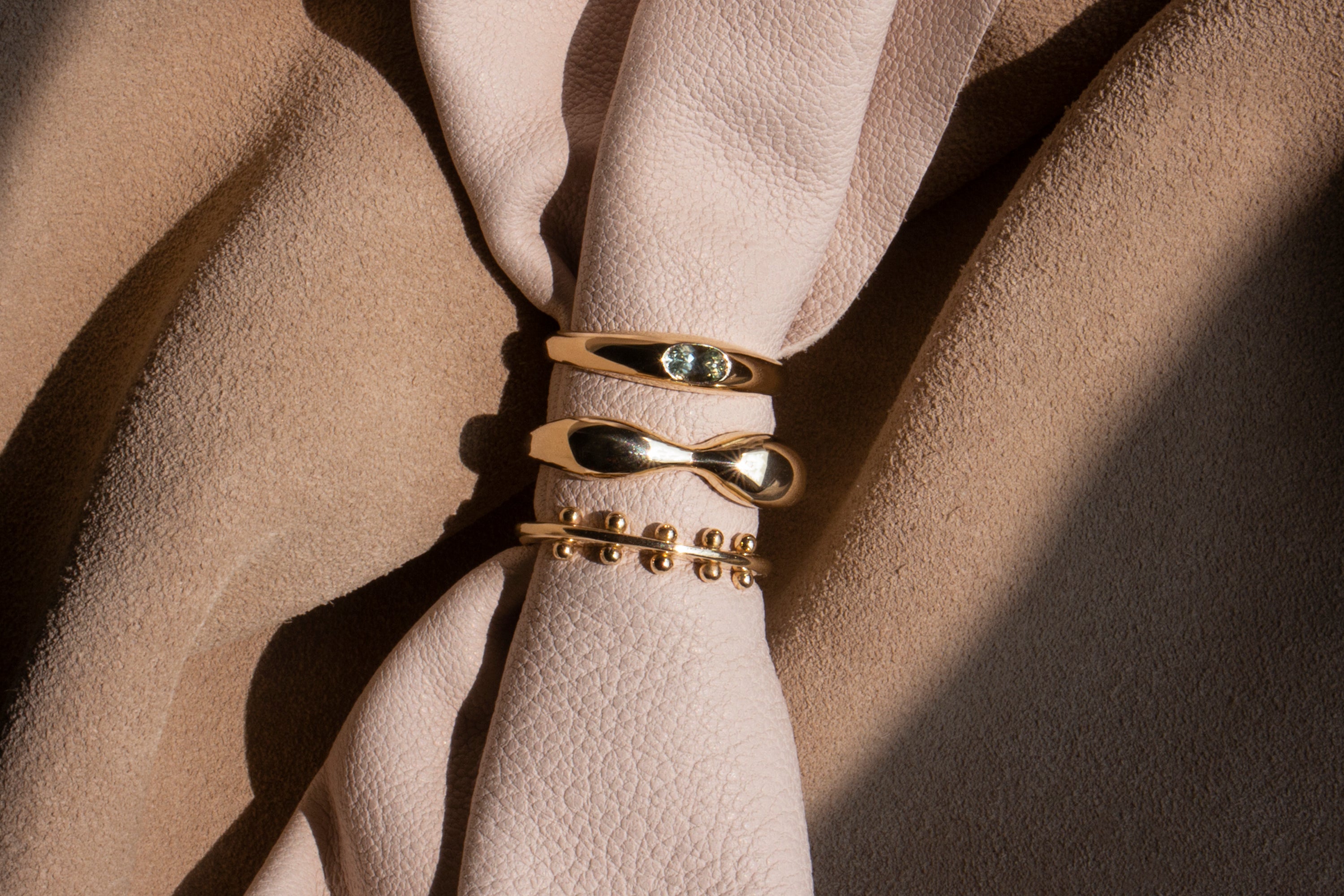 Three gold rings displayed on a piece of cream leather