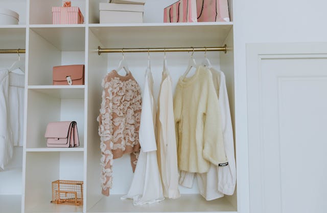 An organized closet with neatly arranged clothes and accessories on shelves and hangers