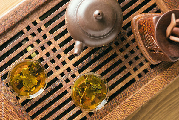 Japanese teapot and teacups full of green tea