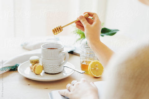 a hand stirring a pot of hot tea