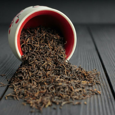 Black tea leaves spilling from a pot