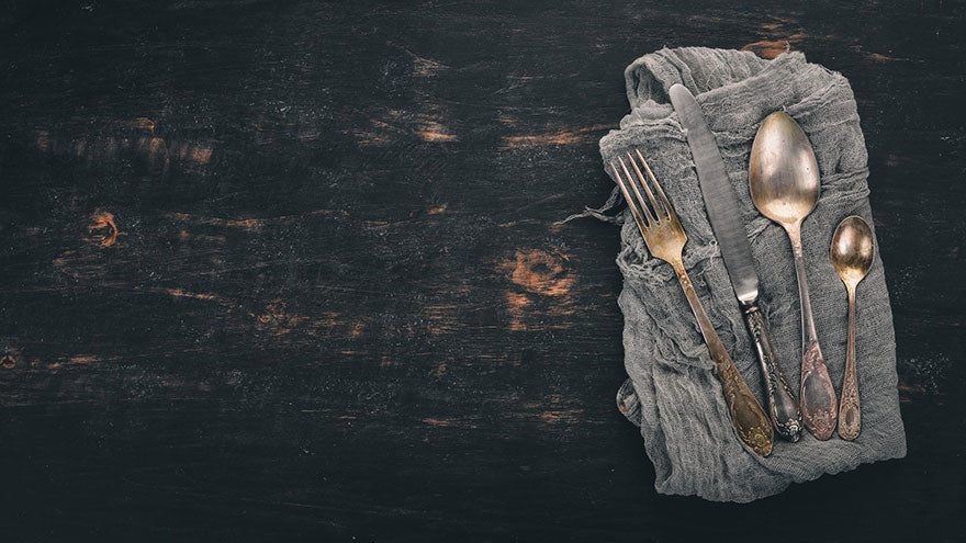 A set of antique flatware on a cloth on a wood table