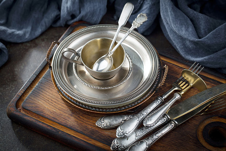 A set of silver flatware with a silver platter and tea cup