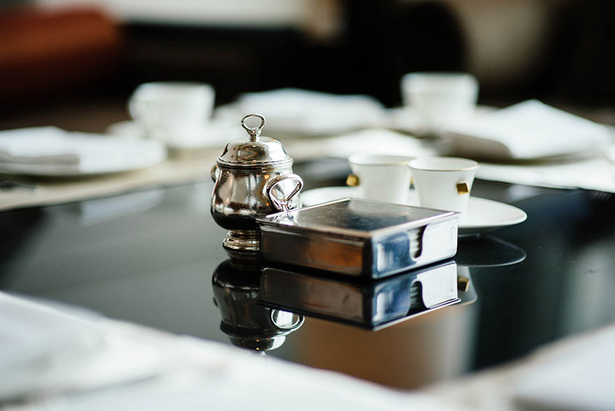 A silver tea pot on a table setting.