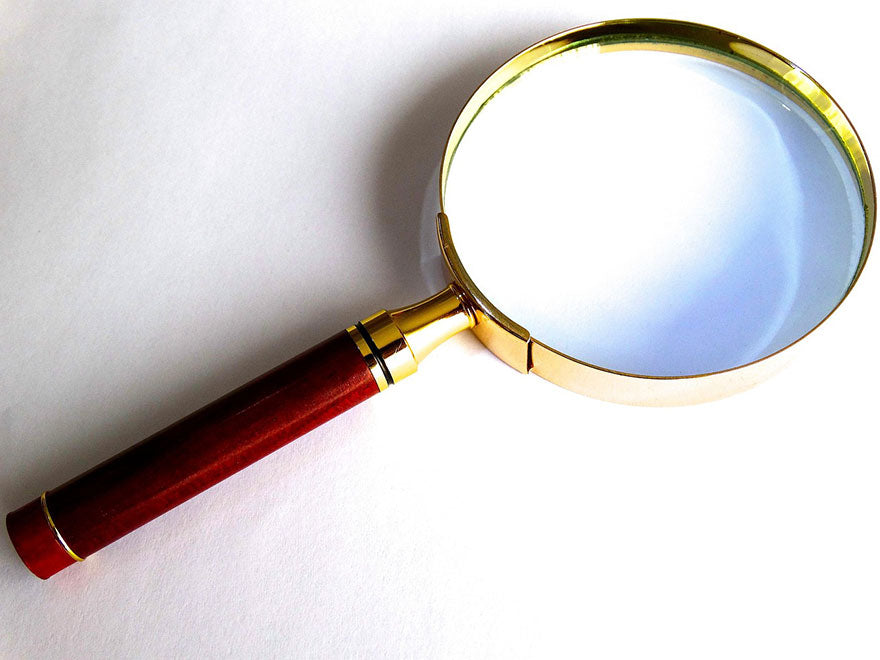 A close-up of a magnifying glass with a red wooden handle and gold rim