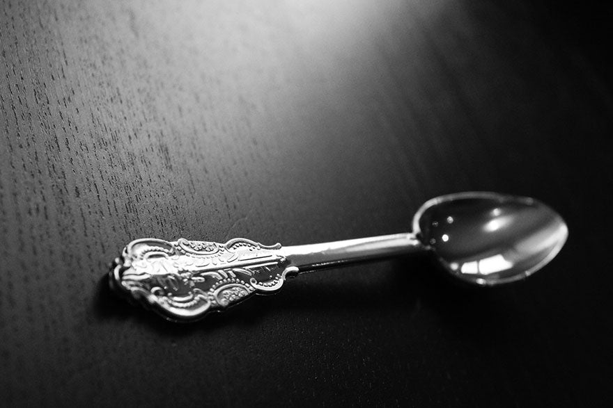 A silver spoon with an ornate handle lying on a wooden surface