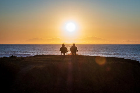 Couple sitting near lake at sunset