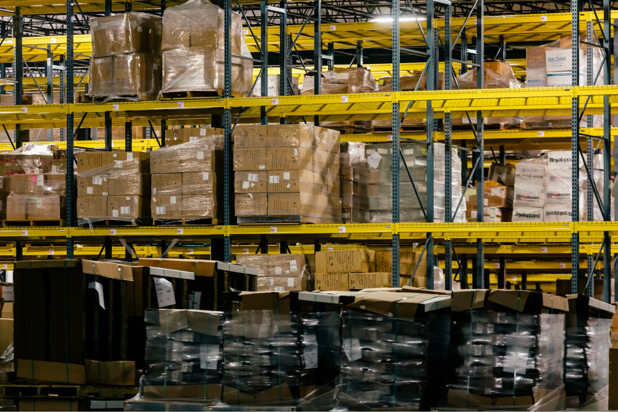 A retail warehouse containing shelves with pallets of cardboard boxes storing inventory.