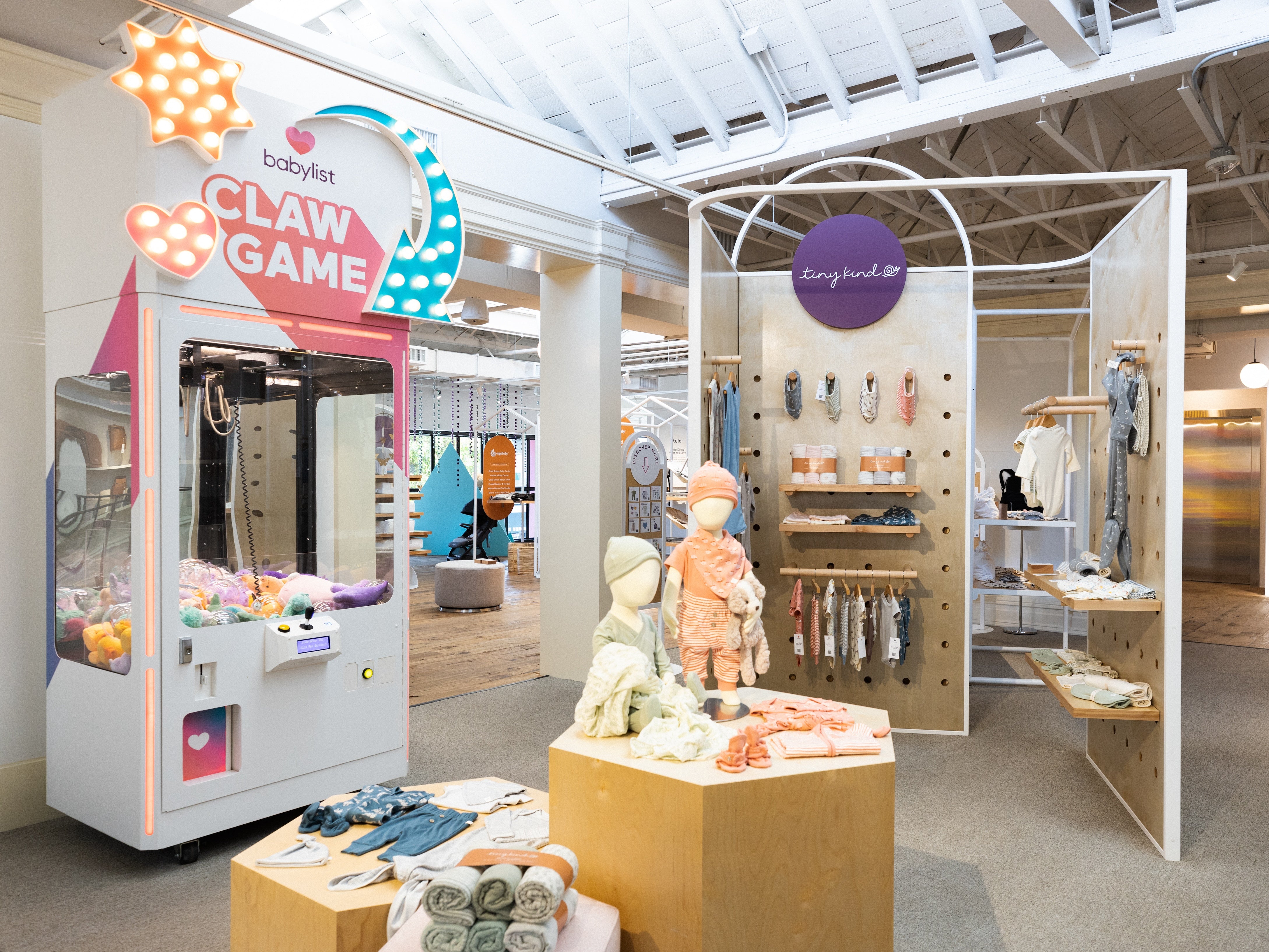 Baby store with baby and toddler clothes on display on mannequins with a colorful arcade game in the background