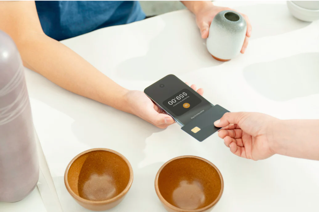 A customer holding their credit card over a mobile point-of-sale device.