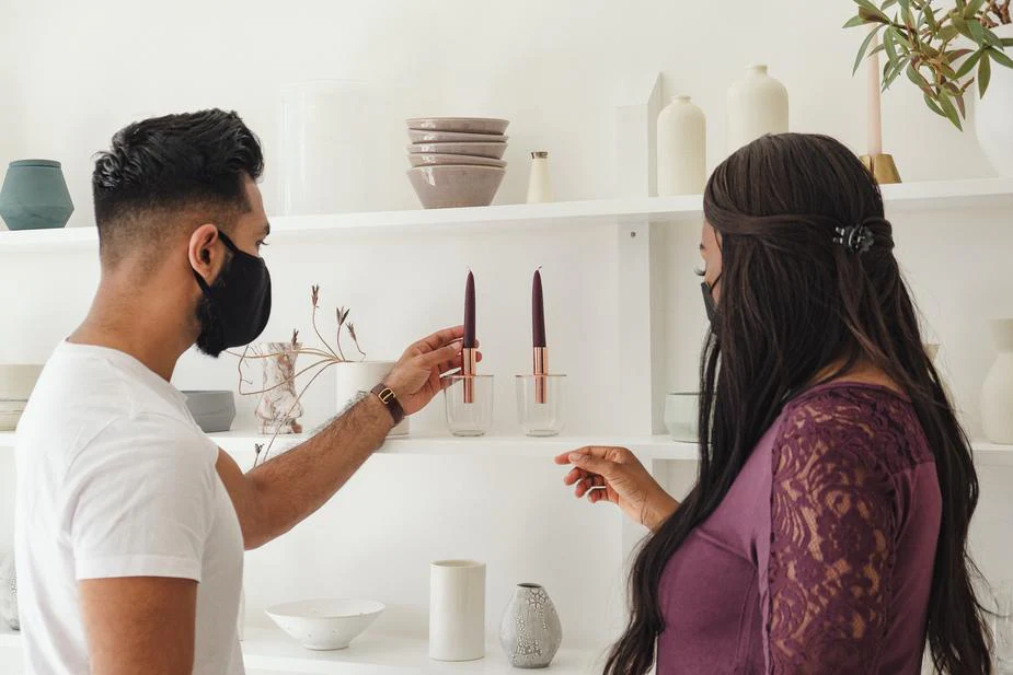 two people admiring a glass candle holder