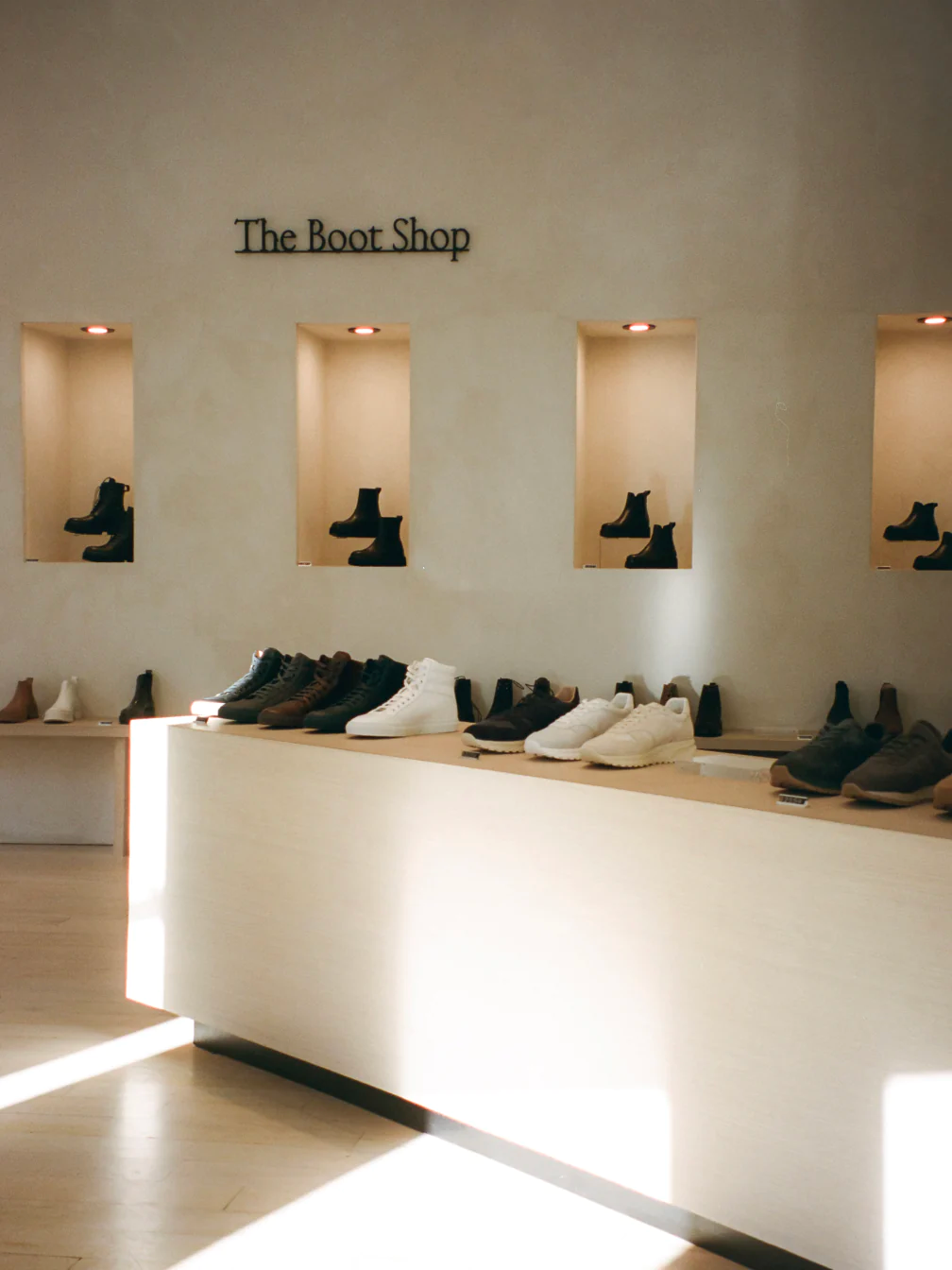 In KOIO's shoe store, boots are displayed in wall alcoves and spotlit by dramatic overhead lights.