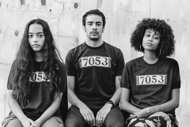 three models of color wear black t-shirts with '7503' handpainted on them.