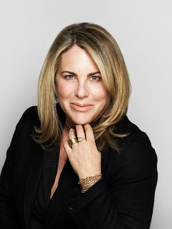 Elegant woman in black, touching her chin, wearing a bracelet and rings.