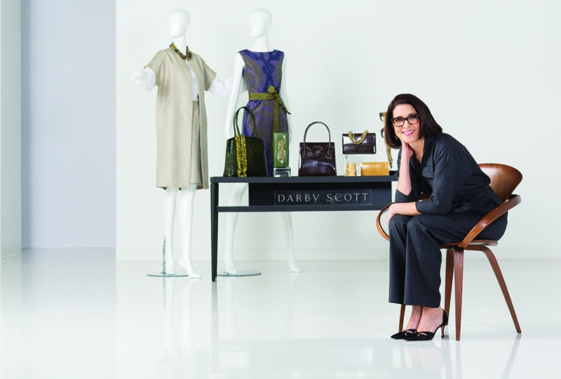 Darby Scott seated in her design studio in front of a display of products