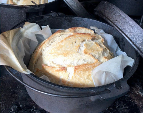 baked bread on parchment in Dutch Oven