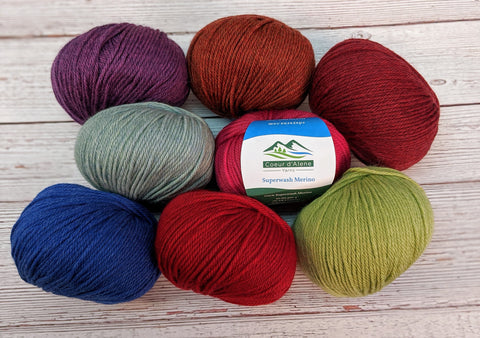 Photo of eight different balls of colorful superwash merino light worsted yarn by Coeur d'Alene Yarns.
