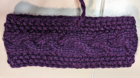 Photo of a purple knit headband with a cable going down the center. Photo shows the nearly invisible seam made with a kitchener stitch join. 