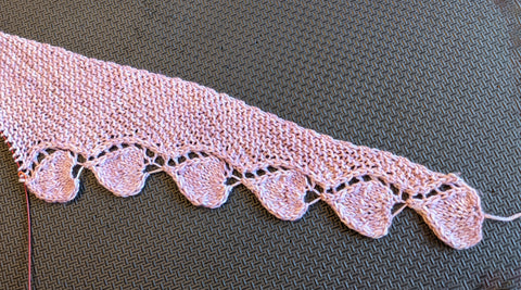 Photo of a pink knit shawl with a heart border, the Knit Your Love Shawl