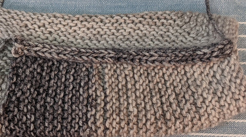 Photo of the left sleeve of the baby surprise jacket in gray where a three stitch applied i-cord was used to seam the shoulder