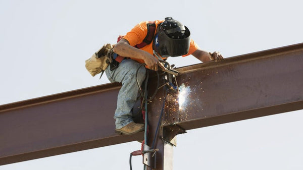 Welder working at height on a construction site in Australia without a safety harness.