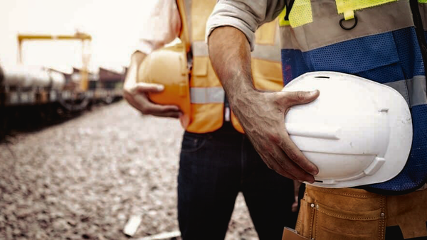 Two Australian workers carrying hard hats and wearing safety equipment on site.