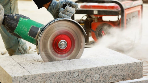 Construction worker cutting stone on a construction site in Australia with correct personal protective equipment.