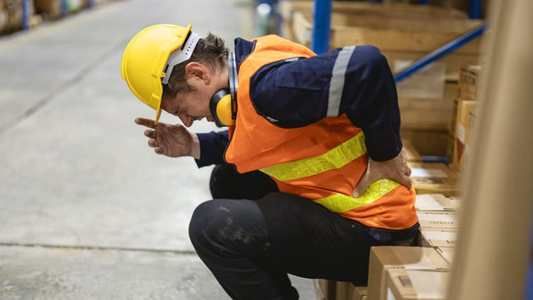 Warehouse worker strains back while working.