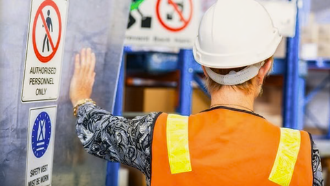 Australian warehouse worker wearing proper safety and personal protective equipment as they enter a warehouse.