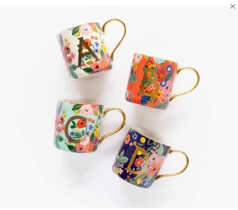 Four decorative floral mugs with a single letter in gold print are displayed against a white background.
