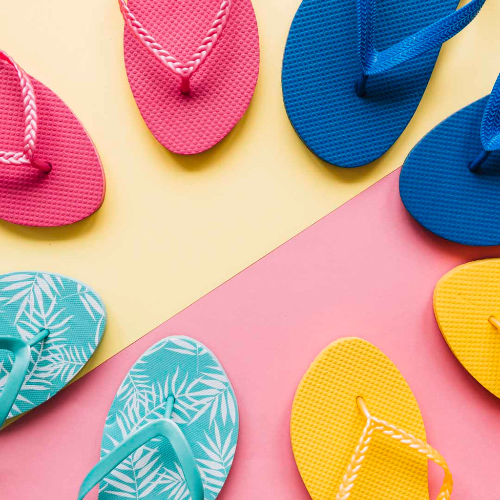 Colorful flip flops forming a circle on a half pink and half yellow floor.