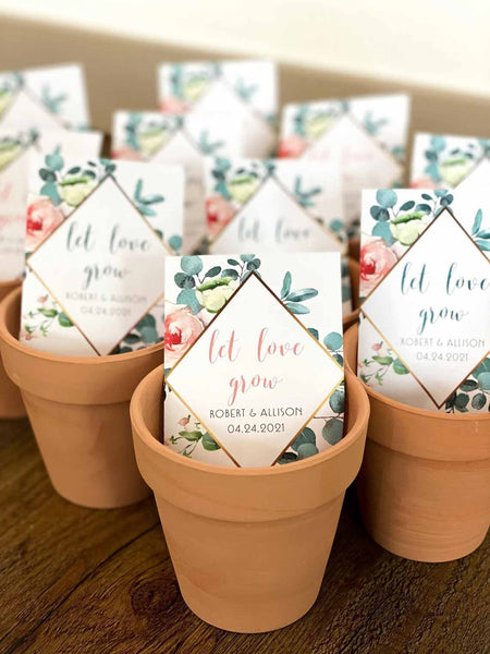 Several small clay flower pots are in a pyramid pattern with each pot containing a pack of seeds that reads, "let love grow"