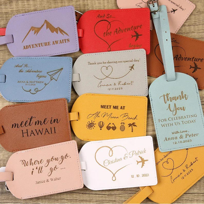 A wooden table is covered with 13 unique and colorful personalized luggage tag destination wedding favors.