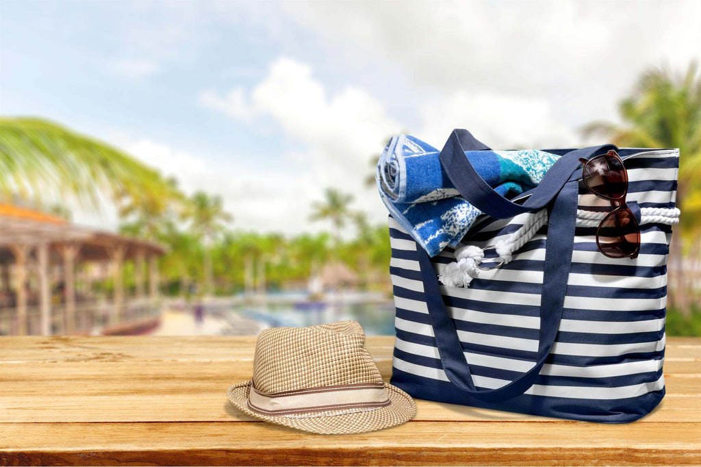 A straw hat and blue and white striped blue tote bag sit on a dock.