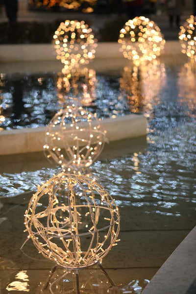 Christmas lights shaped into round balls decorate a pool for wedding decor.