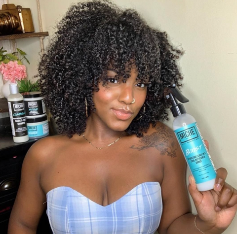 Woman with healthy natural hair holding Miche Beauty Leave in conditioner