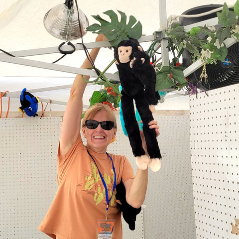 Amazon Ecology volunteer Mary displaying a monkey in the booth at the Philadelphia Folk Festival
