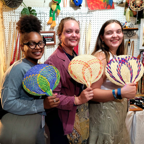 Three women with Amazon chambira palm leaf fans at the Philadelphia Folk Festival