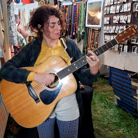 Woman playing song at the Amazon Ecology booth at the Philadelphia Folk Festival 2022