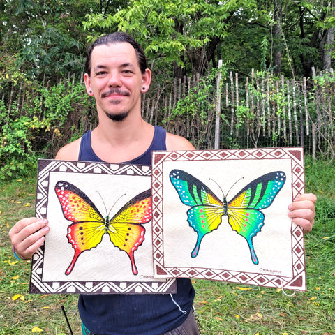 Man displaying two Amazon butterfly paintings done on llanchama bark 