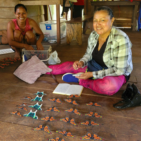 Yully Rojas receiving woven monarch and Urania butterflies made by Brillo Nuevo artisans