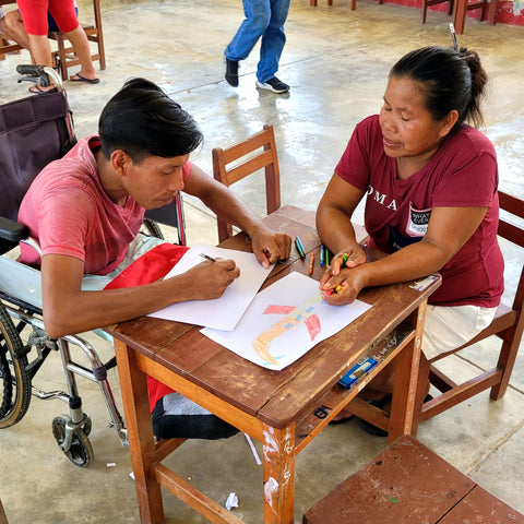 Artisan explaining how to draw an airplane to fellow artisan at Puca Urquillo workshop