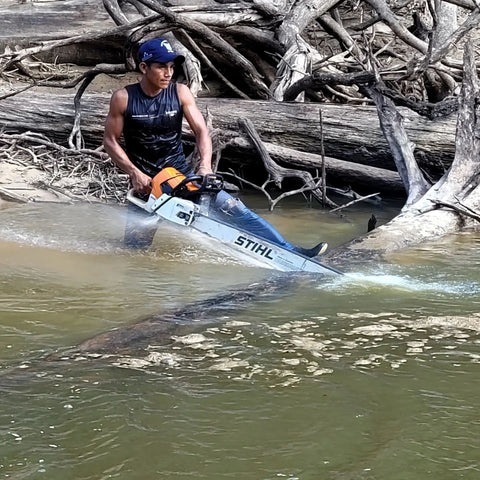 Using chainsaw to cut log blocking channel down Yaguasyacu River