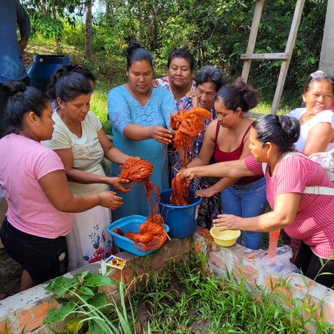 Artisans dyeing rust color chambira palm fiber for bluebird ornaments