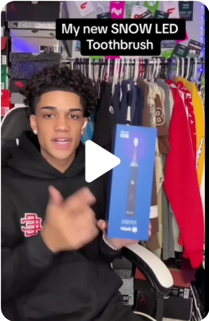 Person holding a box of a SNOW LED Toothbrush in a room full of clothes and shoe boxes.