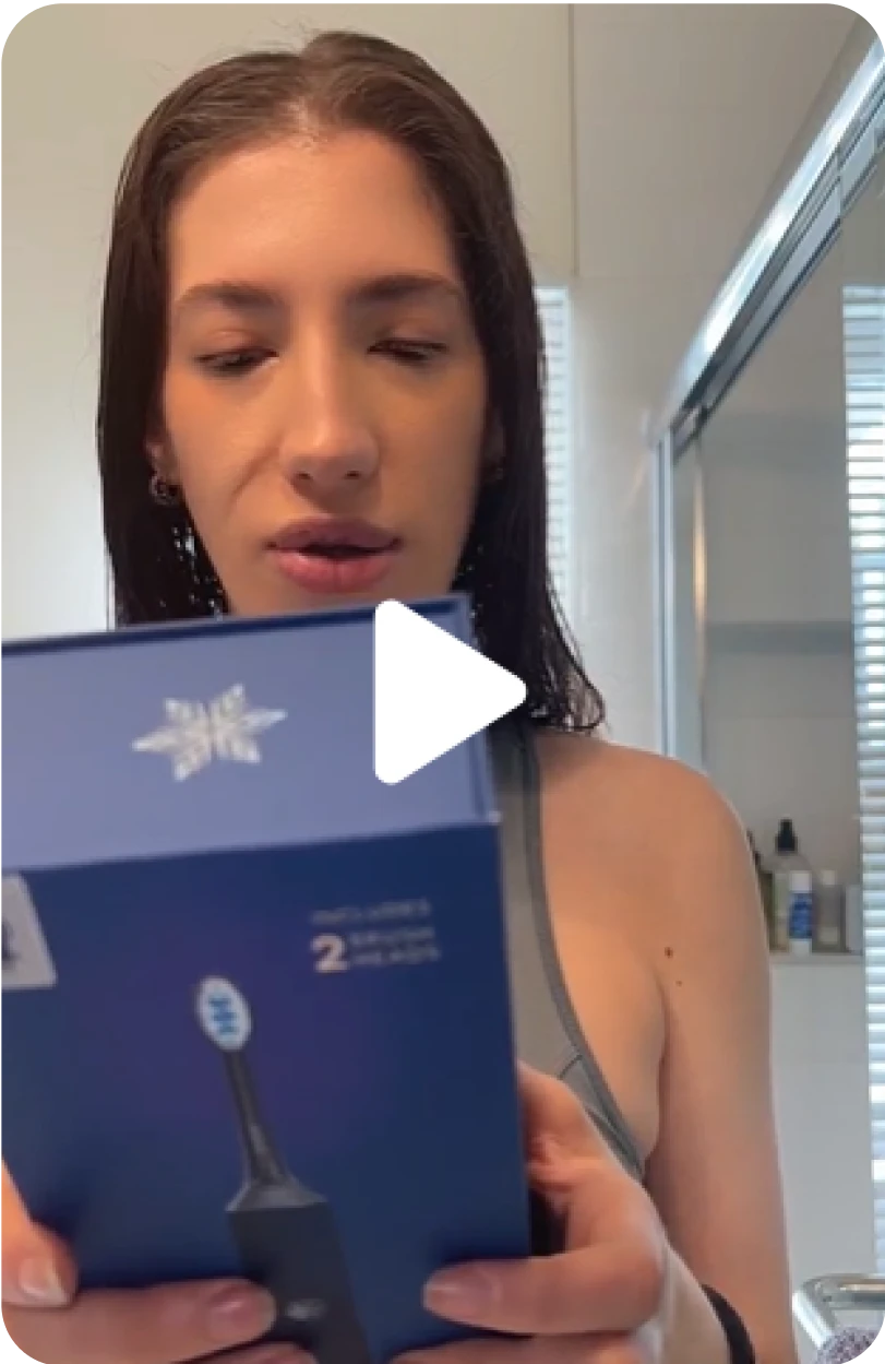 Person holding a blue box with a toothbrush in a bathroom.