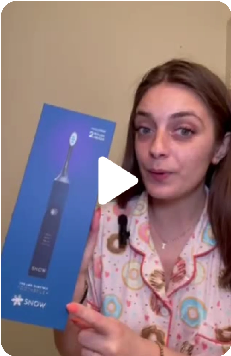 Person holding a Snow toothbrush box, giving a product review.