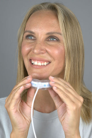 Women smiling while holding a snow teeth whitening tray