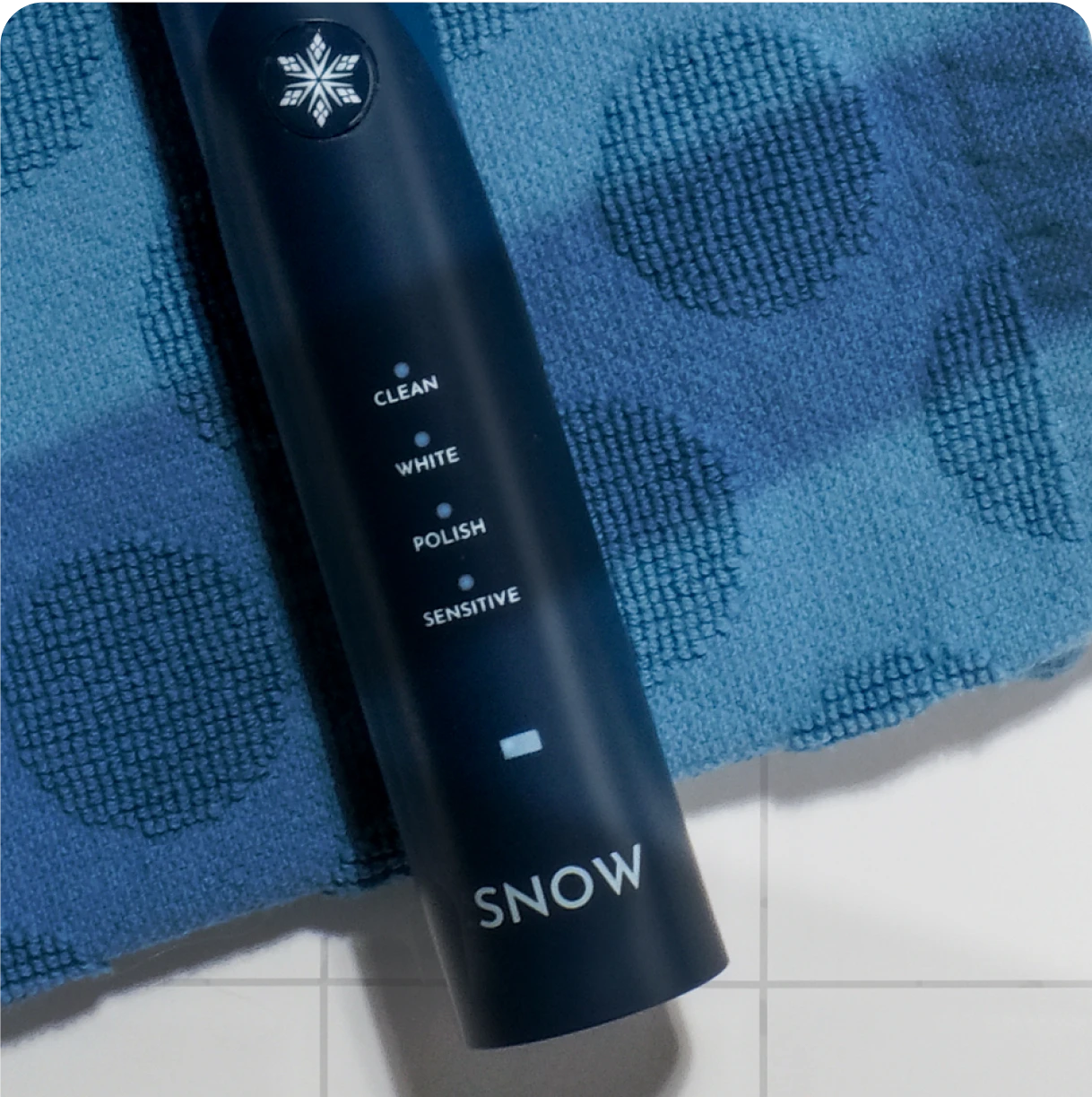 Dark blue electric toothbrush on a polka-dot towel.