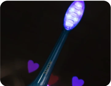 A blue toothbrush with illuminated bristles against a dark background with heart shapes.